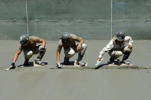 Trys vyrai betonuoja grindis.