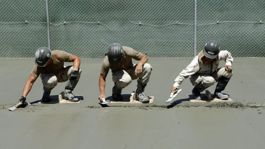 Trys vyrai betonuoja grindis.